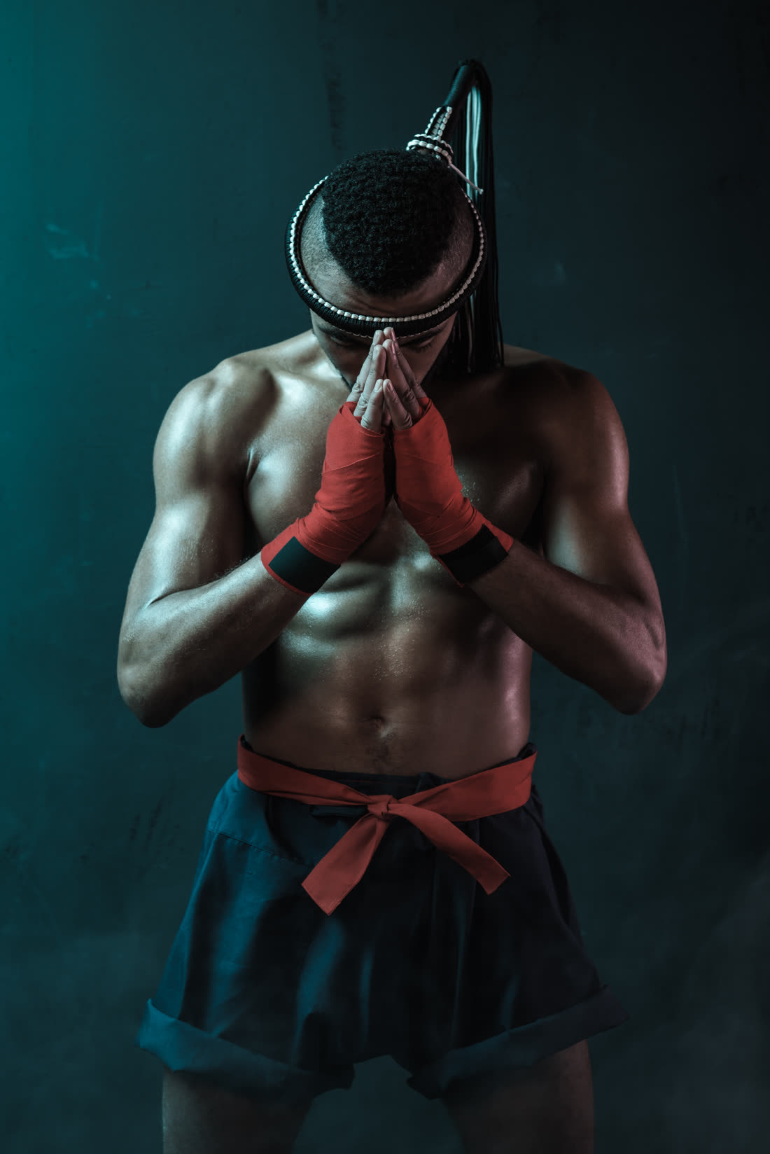 A Muay Thai fighter standing in the wai kru, hands pressed together in respect.